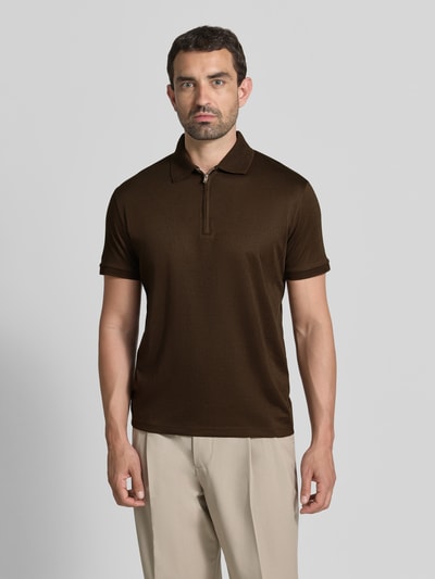 Männermodel trägt Regular Fit Poloshirt aus Baumwoll-Mix Modell 'FAVE' von Selected Homme in Dunkelbraun, beige Hose, Ganzkörperansicht von vorne, Herren Poloshirt von Selected Homme