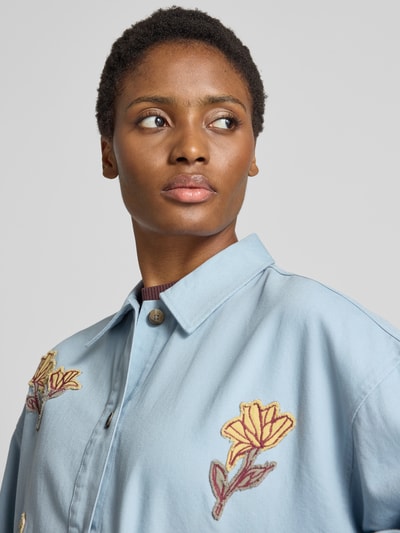 Frauenmodel trägt Regular Fit Jeansjacke mit Motiv-Stitching von Jake*s Casual aus hellblauem Denim mit floralen Applikationen, Nahaufnahme Oberkörper.