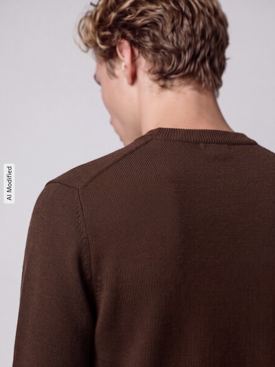 Männermodel trägt braunen Regular Fit Strickpullover aus reiner Baumwolle Modell 'DANE' von Selected, Herren Pullover, Ganzkörperansicht Rückansicht, KI-modifiziertes Bild.