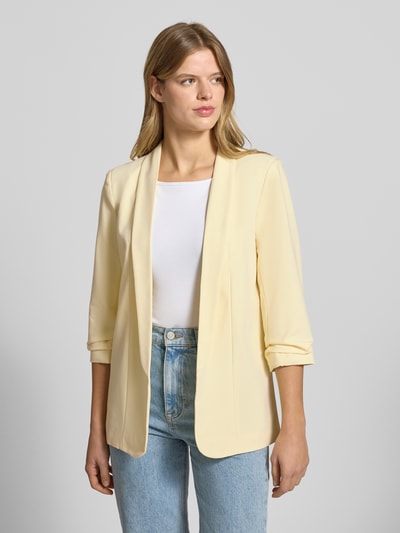 Frauenmodel trägt Regular Fit Longblazer mit Viskose-Anteil Modell 'BOSELLA' von Pieces, Optik: Unifarben, Reverskragen, Schulterpolster, 3/4-Arm, Ärmelabschluss gerafft, Materialverarbeitung: Webstruktur, hellgelb, Ganzkörperansicht von vorne.