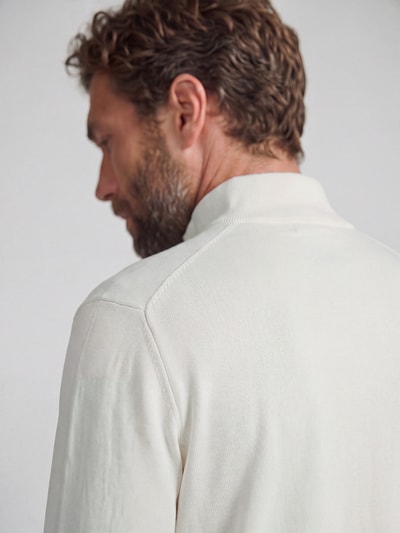 Männermodel trägt Regular Fit Troyer aus reiner Baumwolle von Tommy Hilfiger in Creme mit feiner Struktur, Nahaufnahme Oberkörper. Herren Troyer von Tommy Hilfiger.