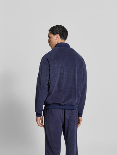 Männermodel trägt Oversized Sweatjacke aus Baumwolle von RHUDE in Dunkelblau mit Frottee, elastische Abschlüsse, Rückenansicht, Ganzkörperansicht Rückansicht.