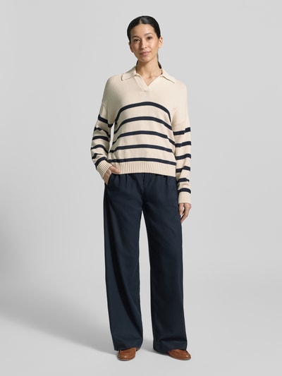 Modelka nosi Regular Fit Strickpullover aus Baumwoll-Mix Modell 'PANFILO' od Weekend Max Mara, beżowy w granatowe paski, dzianina, kołnierzyk koszulowy, długi rękaw, tekstura prążkowana, krój regular fit, widok całej sylwetki z przodu.