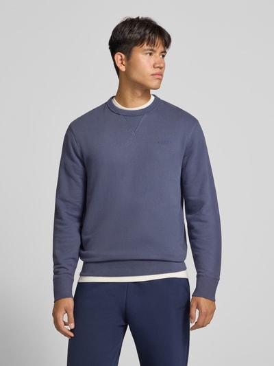 Männermodel trägt Sweatshirt aus Baumwoll-Mix von Superdry in Blau mit Rundhalsausschnitt, lockerer Passform, Ganzkörperansicht von vorne. Rückenlänge 66 cm, Ärmellänge 62 cm, Label-Stitching, elastische Abschlüsse.