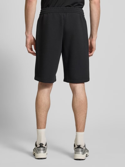 Männermodel trägt Shorts mit elastischem Bund von EA7 Emporio Armani in Schwarz, Material-Mix, Regular Fit, Ganzkörperansicht Rückansicht.