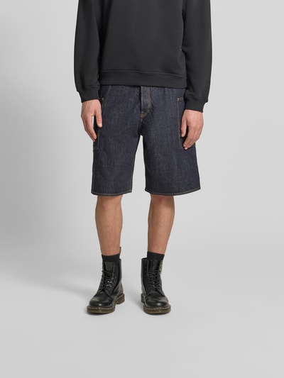 Männermodel trägt Straight Fit Shorts in Denim-Optik von Kenzo aus reiner Baumwolle mit Cargo-Taschen, Knopf- und Reißverschluss, Ganzkörperansicht von vorne.