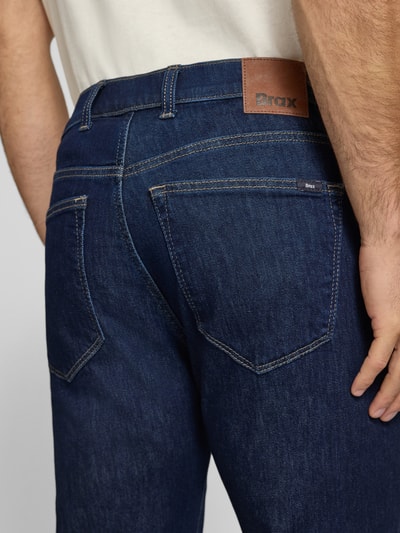 Männermodel trägt Relaxed Fit Jeans aus Baumwoll-Mix Modell 'Clint' von Brax in dunklem Blau, sichtbare Kontrastnähte, Detailaufnahme Rückansicht, Herren Wide & Loose Fit Jeans von Brax.