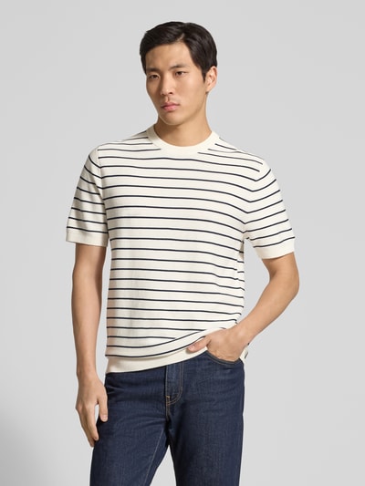 Männermodel trägt Strickshirt mit geripptem Rundhalsausschnitt von MCNEAL, Reine gewachste Baumwolle, Gerader-Schnitt, Ganzkörperansicht von vorne.