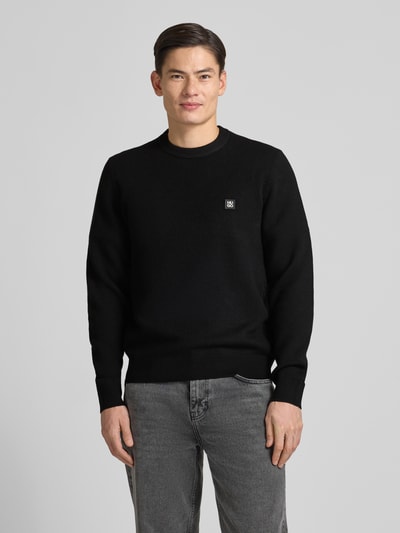 Męski model nosi czarny Regular Fit Strickpullover mit Schurwoll-Anteil Modell 'SETAL' od HUGO, faktura dzianinowa, widok całej sylwetki z przodu.