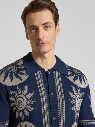 Männermodel trägt Strickshirt mit Polokragen und Knopfleiste von Scotch & Soda im Allover-Look, Baumwoll-Viskose-Mix, Nahaufnahme Oberkörper.