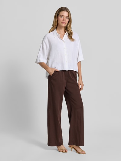 Kobiece model prezentuje spodnie materiałowe z mieszanki bawełny z dodatkiem streczu OPUS PANTS, krój loose fit, model 'Mucia Base', kolor brązowy, z wpuszczanymi kieszeniami francuskimi i tylnymi kieszeniami z wypustką, elastyczny pas, szerokość w rozmiarze 36: 31 cm, długość wewnętrzna nogawki: 80 cm, widok całej sylwetki z przodu.