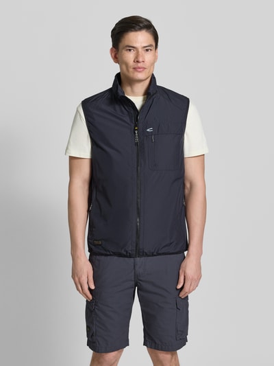 Männermodel trägt Regular Fit Weste mit gefüttertem Stehkragen von camel active in Dunkelblau, mit Brusttasche, Reißverschluss, Eingrifftaschen, elastischer Bund, Rückenlänge 64 cm, Schulterbreite 45 cm, Brustweite 60 cm, Ganzkörperansicht von vorne.