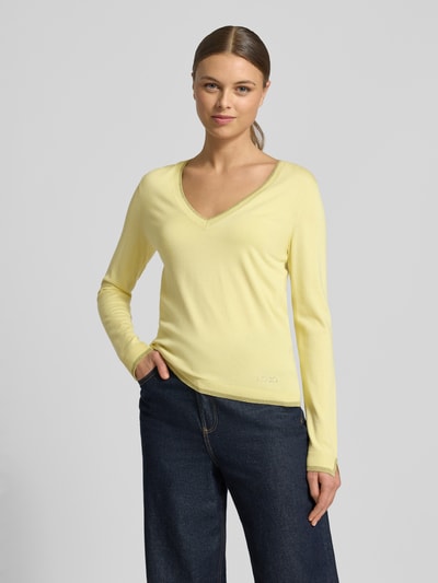 Frauenmodel trägt Slim Fit Longsleeve aus Viskose-Mix mit V-Ausschnitt von Liu Jo White in Hellgelb, Logo-Detail, elastische Abschlüsse, Ganzkörperansicht von vorne.