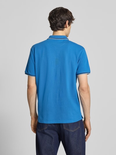 Männermodel trägt Slim Fit Poloshirt mit Label-Stitching von CHAMPION in Blau, Reine Baumwolle, Rückenlänge 73 cm, Ganzkörperansicht Rückansicht.