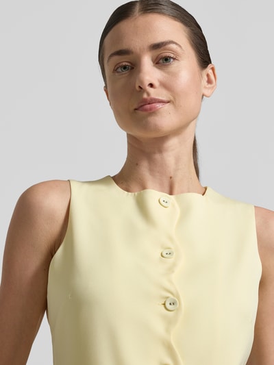 Vrouwenmodel draagt Weste met ronde hals en paspelzakken van Little Mistress, materiaalmix met stretch, slim fit, knoopsluiting, maat 36, lichtgeel, gladde textuur, nahaufnahme bovenlichaam.