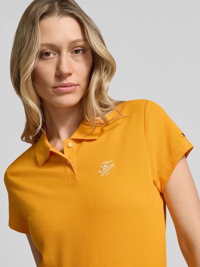 Vrouwenmodel draagt Slim Fit Poloshirt aus Baumwoll-Mix van Tommy Hilfiger in effen kleuren met gestikt logo, piqué katoenmix, korte mouw, 2-knoopsluiting, nahaufnahme bovenlichaam.