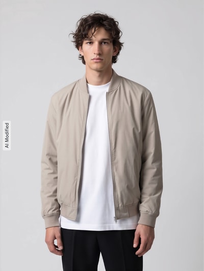 Männermodel trägt Regular Fit Bomberjacke mit Baseball-Kragen Modell 'CHARLES' von Selected, helle Beige-Farbtöne, Ganzkörperansicht von vorne, KI-modifiziertes Bild. Herren Bomberjacke / Blouson.