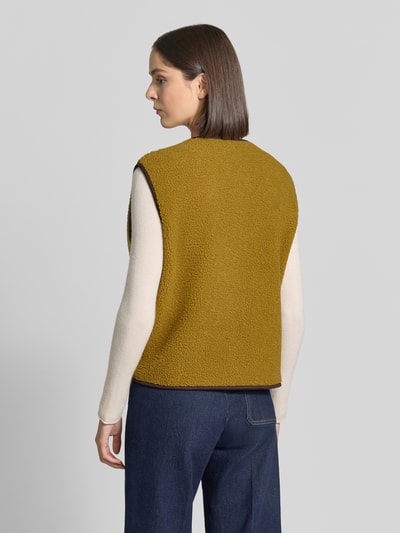 Vrouwenmodel draagt Relaxed Fit bodywarmer met doorlopende knoopsluiting van Christian Berg Woman, Teddybont, ronde hals, mouwloos, zij-steekzakken, kleuren mosterdgeel en crème, textuur zacht en grof, Ganzkörperansicht Rückansicht.