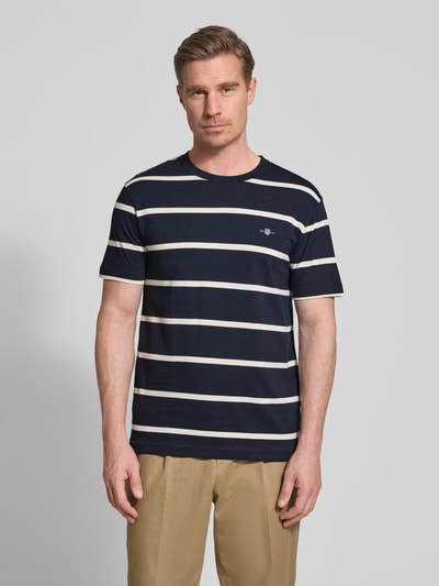 Męski model nosi Regular Fit T-Shirt mit Logo-Stitching od Gant, bawełna, okrągły dekolt, długość tyłu 68 cm w rozmiarze M, całkowity widok z przodu.