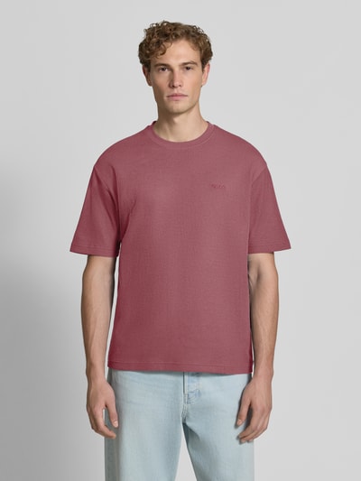 Männermodel trägt Regular Fit T-Shirt aus reiner Baumwolle Modell 'Te_Rib' von BOSS, BOSS Orange; mattes Rosa, glatte Struktur, Ganzkörperansicht von vorne.