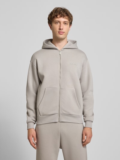 Männermodel trägt Regular Fit Sweatjacke mit Känguru-Tasche von REVIEW in Hellgrau, Baumwoll-Mix, Reißverschluss, Ganzkörperansicht von vorne.
