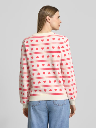 Frauenmodel trägt Relaxed Fit Pullover mit Allover-Motiv-Stitching Modell 'Brielle' von ICHI in Strick-Optik, cremefarben mit roten und rosafarbenen Herz-Motiven und elastischen Abschlüssen, Rundhalsausschnitt, Rückenlänge und Ärmellänge gemäß Angabe, Ganzkörperansicht Rückansicht.