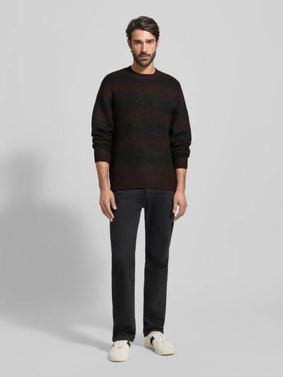 Männermodel trägt Strickpullover mit Rundhalsausschnitt von Jack & Jones Premium in Schwarz, lockerer Schnitt, melierte Textur, Ganzkörperansicht von vorne.