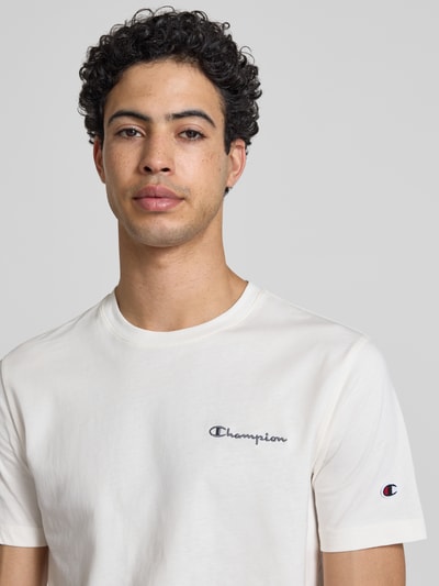 Männermodel trägt T-Shirt mit Label-Stitchings und Rundhalsausschnitt von CHAMPION in Weiß, Reine Baumwolle, Regular-Fit, Nahaufnahme Oberkörper. Rückenlänge bei Größe M: 69 cm.