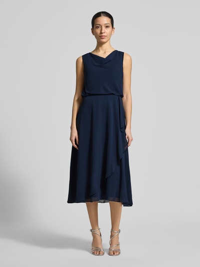 Frauenmodel trägt knielanges Cocktailkleid mit Wasserfall-Ausschnitt von Christian Berg Cocktail aus dunkelblauem Chiffon, taillierter Schnitt, Wickeloptik am Saum, breite Träger, Haken- und Reißverschluss hinten, Rückenlänge 120 cm, Brustweite 45 cm, Ganzkörperansicht von vorne.