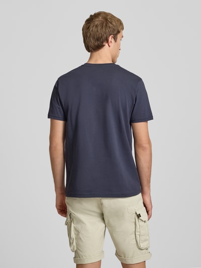 Männermodel trägt T-Shirt mit Logo und Rundhalsausschnitt von Alpha Industries aus Reine Baumwolle, Regular-Fit, Rückenlänge 67 cm, Ganzkörperansicht Rückansicht.