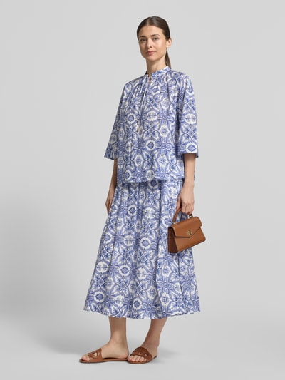 Kobiece model nosi bluzkę Regular Fit Bluse mit Schlüsselloch-Ausschnitt Modell 'Beyda' von JOOP! z mieszanki modalu, wzór na całej powierzchni, wycięcie w kształcie łezki, wiązanie, rękaw o dł. 3/4; długość tyłu w rozmiarze 36: 58 cm, długość rękawów: 32 cm; jasnoniebieskie i białe, miękka tekstura, widok całej sylwetki z przodu.