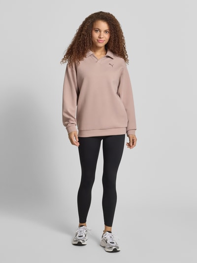 Frauenmodel trägt Relaxed Fit Poloshirt mit Lyocell-Anteil von PUMA in Rosé, Elastischer-Material-Mix, Logo-Detail, Polo-Kragen, Langärmelig, elastische Abschlüsse, Ganzkörperansicht von vorne.