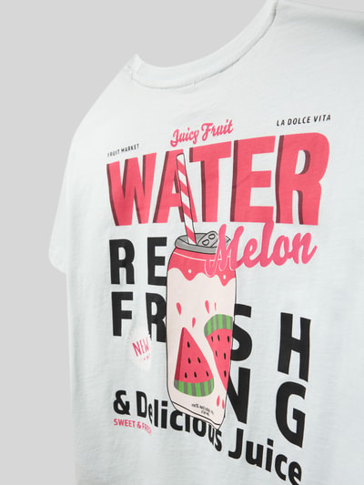 Mädchen trägt Regular Fit T-Shirt aus reiner Baumwolle Modell 'CANA' von Only, Optik: Unifarben, Motiv-Print, Nahaufnahme Oberkörper.