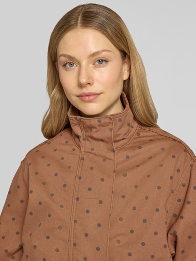 Frauenmodel trägt Jacke mit verdecktem Reißverschluss Modell 'DOTS' von Mango aus reiner Baumwolle, braun mit Punkten, Nahaufnahme Oberkörper.