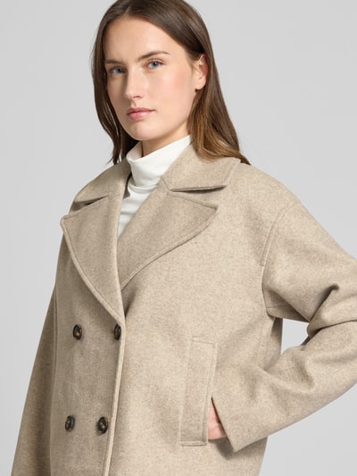Frauenmodel trägt Cropped Trenchcoat mit doppelreihiger Knopfleiste Modell 'VINCELINE' von Vero Moda in Beige, Boxy Fit, Reverskragen, Nahaufnahme Oberkörper.