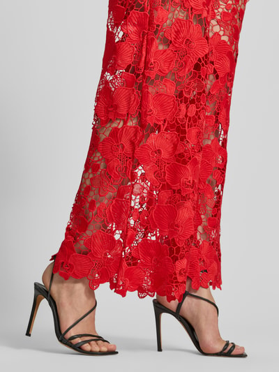 Kobieta nosi Hose aus Spitze Modell 'GALA' od YAS, czerwona koronka, krój regular fit, szerokość w rozmiarze 36: 38 cm, długość nogawki wewnętrznej: 82 cm, z elastycznym pasem, zbliżenie na dolną część nóg.