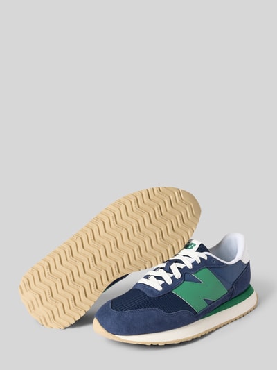 Produktfoto, Sneaker mit Logo-Detail von New Balance in Blau und Grün, strukturierte Sohle, abgerundete Form, Schnürverschluss, Herren Sneaker, Absatzhöhe 2 cm, Schafthöhe 8 cm, Schaftweite 9 cm, weiße und beigefarbene Akzente, strukturierte Textur