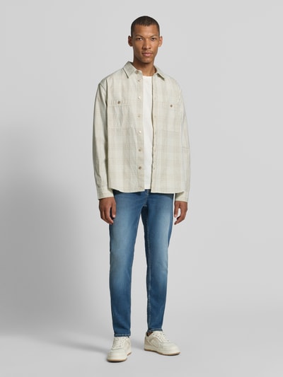 Männermodel trägt Tapered Fit Jeans aus Baumwoll-Lyocell-Mix Modell 'AARJO TARPA' von ARMEDANGELS in mittlerem Blau, Ganzkörperansicht von vorne. Herren Tapered Fit Jeans von ARMEDANGELS.