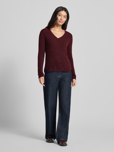 Frauenmodel trägt Slim Fit Strickpullover aus Material-Mix mit Woll-Anteil von MOS MOSH in Bordeaux mit V-Ausschnitt, elastische Abschlüsse, kombiniert mit Jeans, Ganzkörperansicht von vorne.