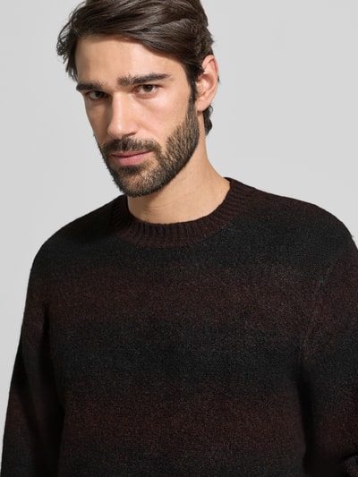 Männermodel trägt Strickpullover mit Rundhalsausschnitt von Jack & Jones Premium in Dunkelbraun-Schwarz, lockerer Schnitt, Nahaufnahme Oberkörper.