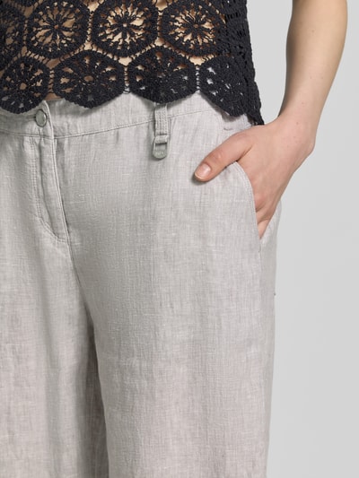 Frauenmodel trägt Culotte aus Leinen mit Eingrifftaschen Modell 'Nora' von MAC in hellem Grau, Label-Detail, Knopf-Reißverschluss, Nahaufnahme Oberkörper. Bundweite 44 cm, Innenbeinlänge 67 cm, Wide-Fit, reine Leinenstruktur.