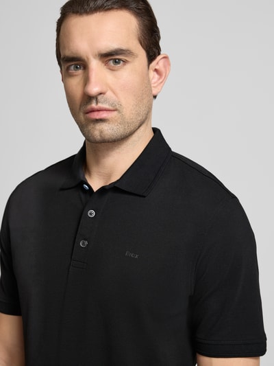 Männermodel trägt Regular Fit Poloshirt mit Logo-Detail Modell 'Pete' von BRAX aus elastischem Baumwoll-Mix, kurzärmelig, Nahaufnahme Oberkörper.