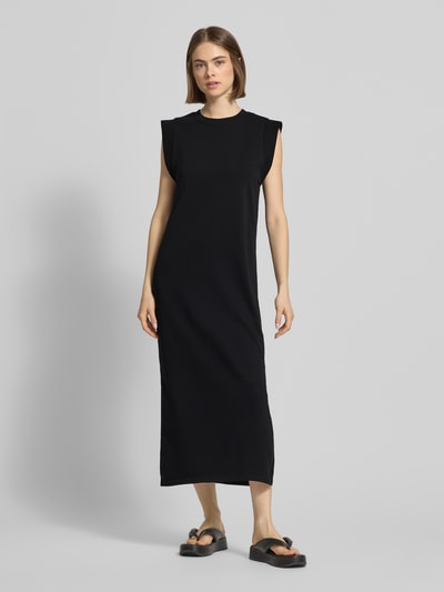 Modelka kobieca ma na sobie Regular Fit Sweatkleid aus Baumwoll-Mix Modell 'CHILLI SUMMER' od Pieces, czarny, jednolity, krój regular fit, długość maxi, okrągły dekolt, bez rękawów, bawełniany miks, rozcięcia po bokach, z materiału typu dres, widok całej sylwetki z przodu.