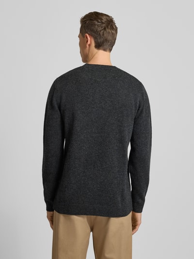 Männermodel trägt Strickpullover aus Lammwolle Modell 'Tay' von Wood Wood, Regular-Fit, dunkle Farbe, Ganzkörperansicht Rückansicht.