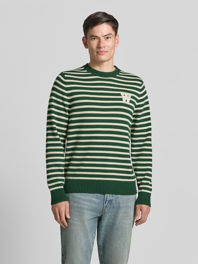 Männermodel trägt Strickpullover mit Rundhalsausschnitt von Wood Wood aus Reine Baumwolle, Gerader-Schnitt, Label-Stitching, Ganzkörperansicht von vorne