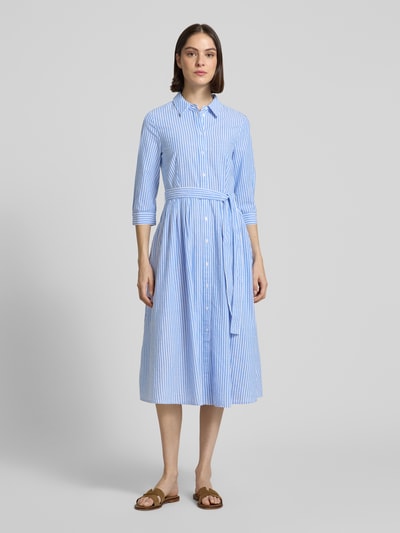 Frauenmodel trägt Hemdblusenkleid mit Bindegürtel und 3/4-Arm von Oui aus Reine Baumwolle, A-Linie, Midikleid, Hemdblusenkragen, Knopfleiste, Brustweite 48 cm, Rückenlänge 120 cm, Ärmellänge 46 cm, gestreiftes Muster in Hellblau und Weiß, Ganzkörperansicht von vorne.