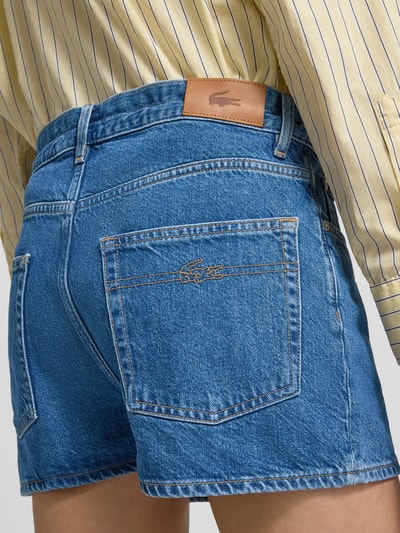 Frauenmodel trägt Regular Fit Jeansshorts aus reiner Baumwolle von Lacoste mit Logo-Patch und Kontrastnähten, Detailaufnahme Rückansicht.