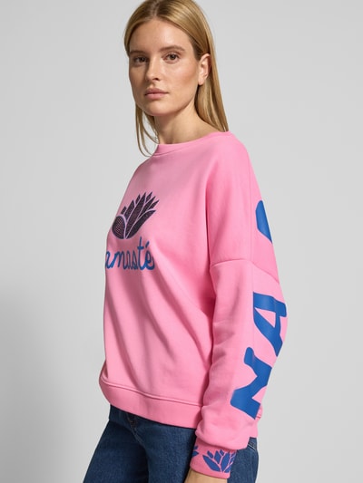 Frauenmodel trägt Oversized Sweatshirt mit gerippten Abschlüssen von miss goodlife in Rosa mit blauen Aufdrucken, Ganzkörperansicht von vorne.