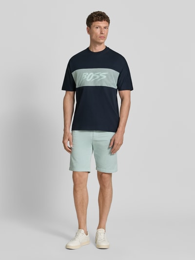Männermodel trägt Regular Fit T-Shirt aus reiner Baumwolle Modell 'TE_BAYMESH' von BOSS Orange in Dunkelblau mit Mesh-Details, unifarben, Rundhals, Label-Print, Jersey-Textur, Ganzkörperansicht von vorne.