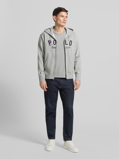 Männermodel trägt T-Shirt mit Logo-Stitching von Polo Ralph Lauren aus reiner Baumwolle in Grau, gerade Passform, Rundhalsausschnitt, Ganzkörperansicht von vorne.